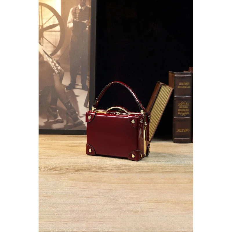 Vintage-style women's handbag in a suitcase design, patent leather, glossy wine red, luxury high-end crossbody shoulder bag